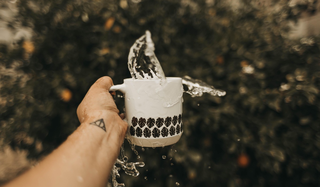 Чашка с водой в руке с татуировкой 