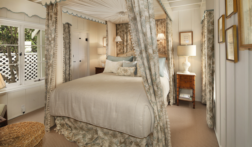 Высокая кровать с занавесками в спальной комнате в пастельных тонах 