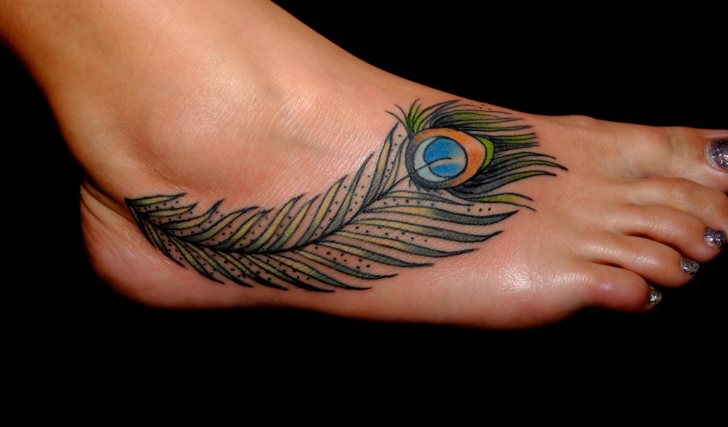 Татуировка перо павлина на ноге на черном фоне