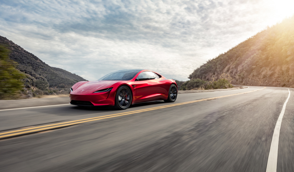 Красный автомобиль Tesla Roadster едет по трассе 