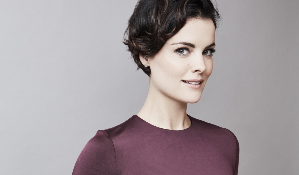 Улыбающаяся девушка, актриса Джейми Александр на сером фоне