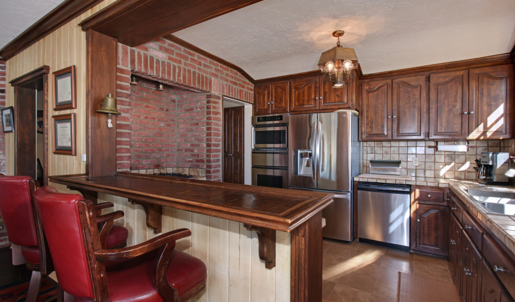 Просторная кухня с деревянной мебелью и кожаными стульями
