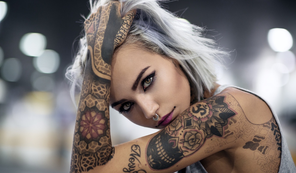 Татуировки на теле красивой девушки с пирсингом в носу