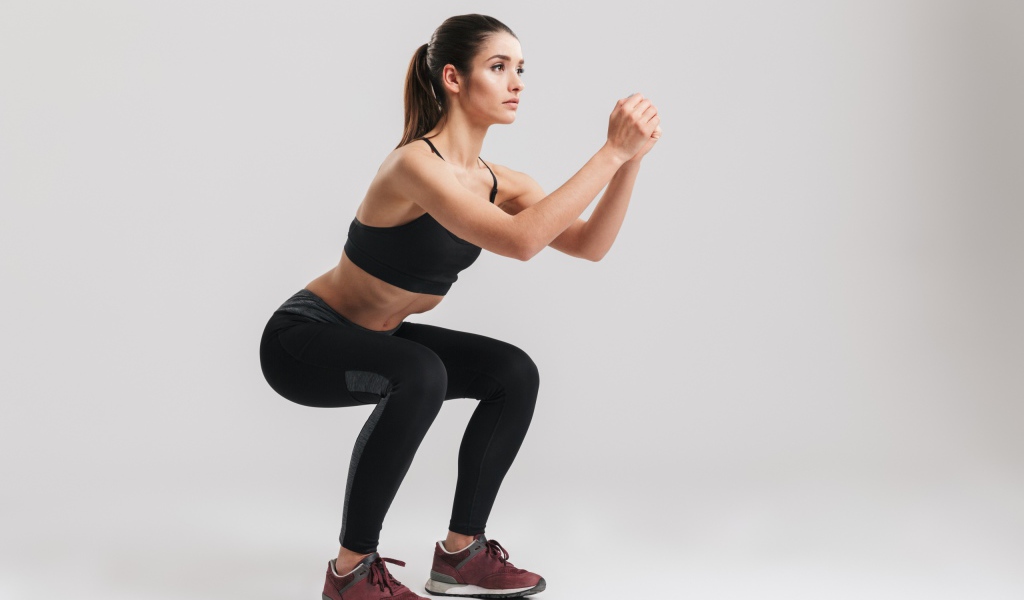 Девушка занимается гимнастикой на сером фоне