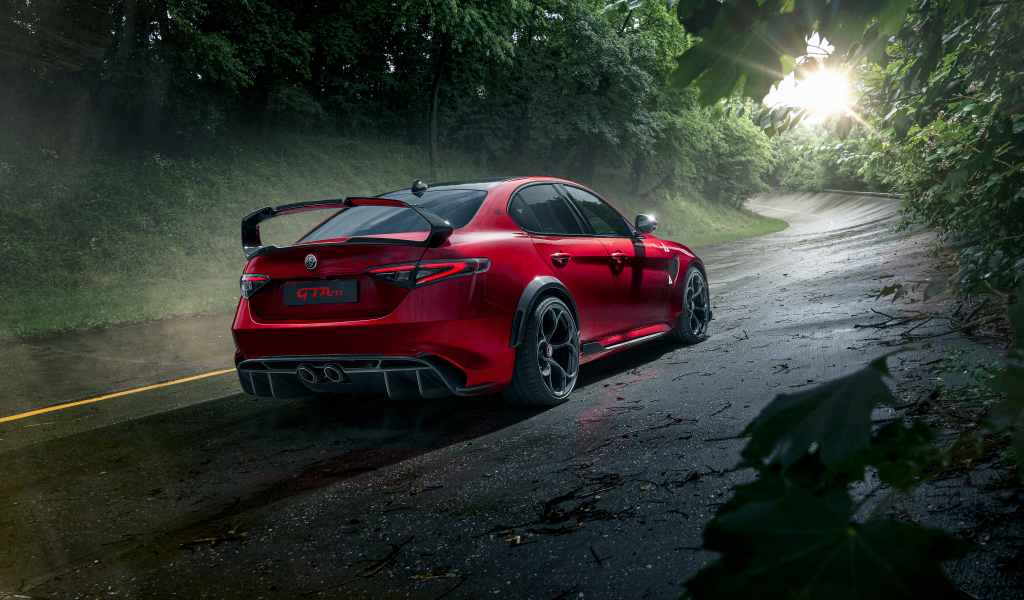 Красный автомобиль Alfa Romeo Giulia GTAm, 2021 года на дороге в лесу