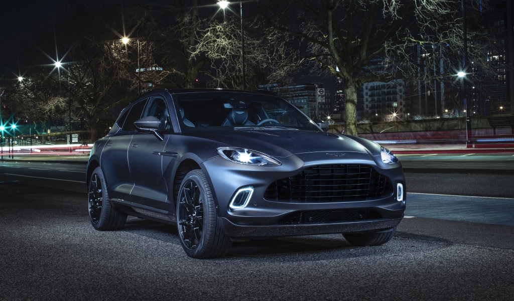 Автомобиль Aston Martin DBX Q Concept 2020 года с включенными фарами вечером
