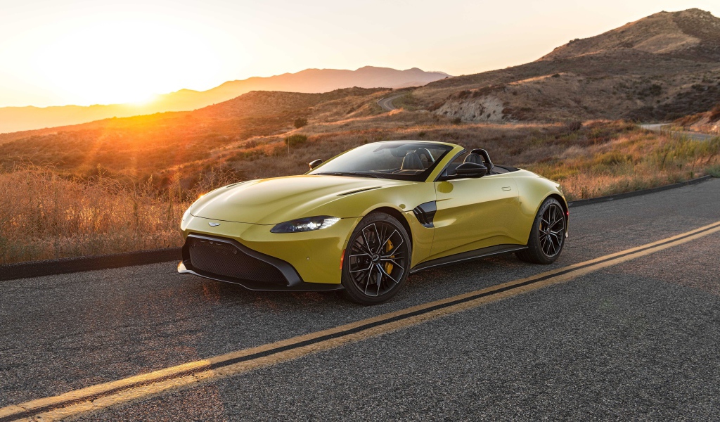 Желтый кабриолет  Aston Martin Vantage Roadster, 2021 года на трассе на рассвете