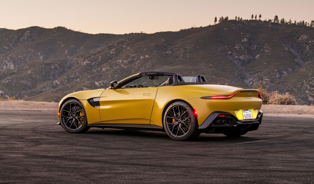 Желтый автомобиль  Aston Martin Vantage Roadster, 2021 года на фоне гор 
