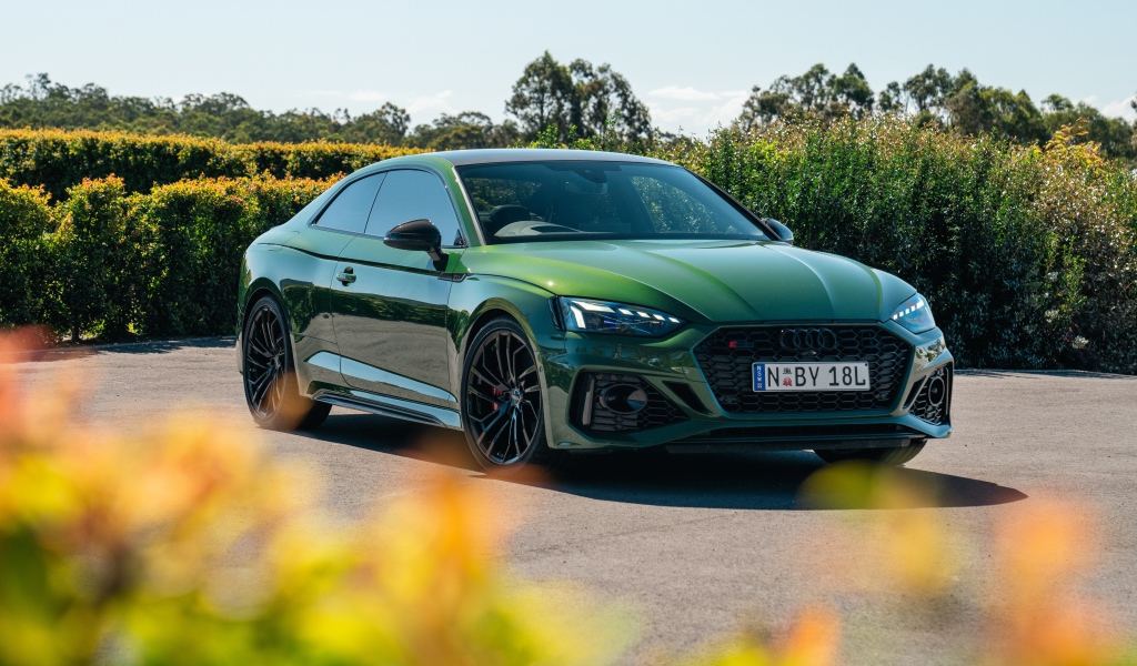 Зеленый автомобиль Audi RS 5 Coupé 2020  года в лучах солнца
