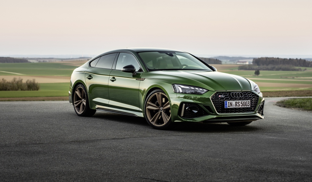 Зеленый автомобиль Audi RS 5 Sportback 2020 года на фоне поля