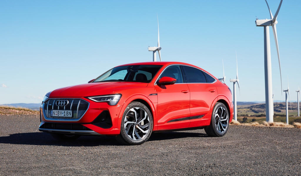 Красный автомобиль Audi E-Tron 50 Quattro Sportback S Line 2020 на фоне ветряных турбин