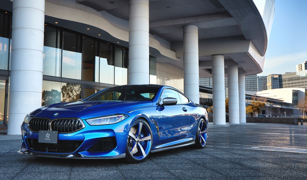 Синий автомобиль BMW M850i XDrive Coupe 2020 года у здания 