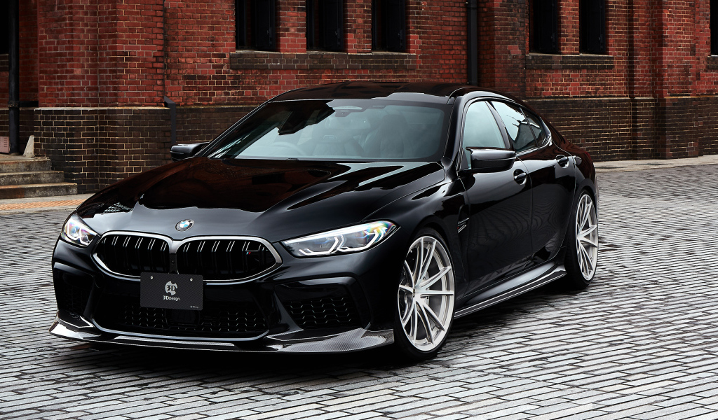 Дорогой черный автомобиль BMW M8 у стены