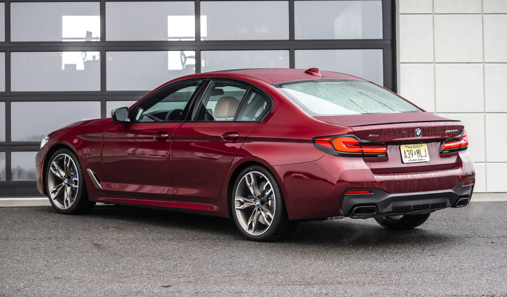 Красный автомобиль BMW M550i XDrive, 2021 года вид сзади
