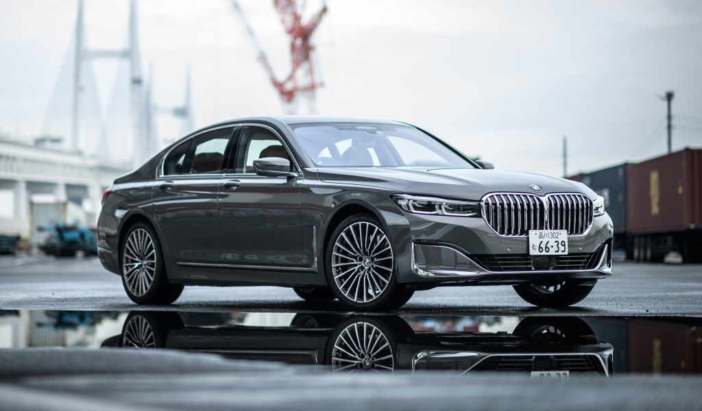Серебристый автомобиль BMW 745e на мокром асфальте 