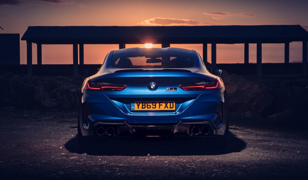 Синий автомобиль BMW M8, 2019 года на фоне заката 