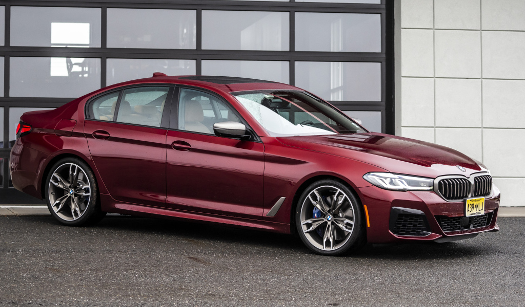 Красный автомобиль BMW M550i XDrive, 2021 года у гаража
