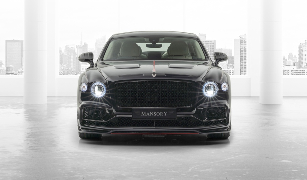 Черный автомобиль Mansory Bentley Flying Spur 2020 года с включенными фарами 