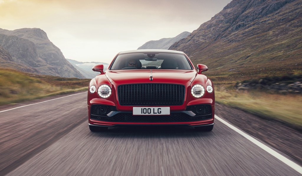 Красный автомобиль Bentley Flying Spur V8 2020 года на дороге в горах 