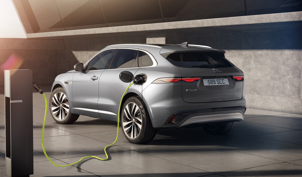 Серебристый автомобиль Jaguar F-Pace P400e AWD 2020 года на заправке 