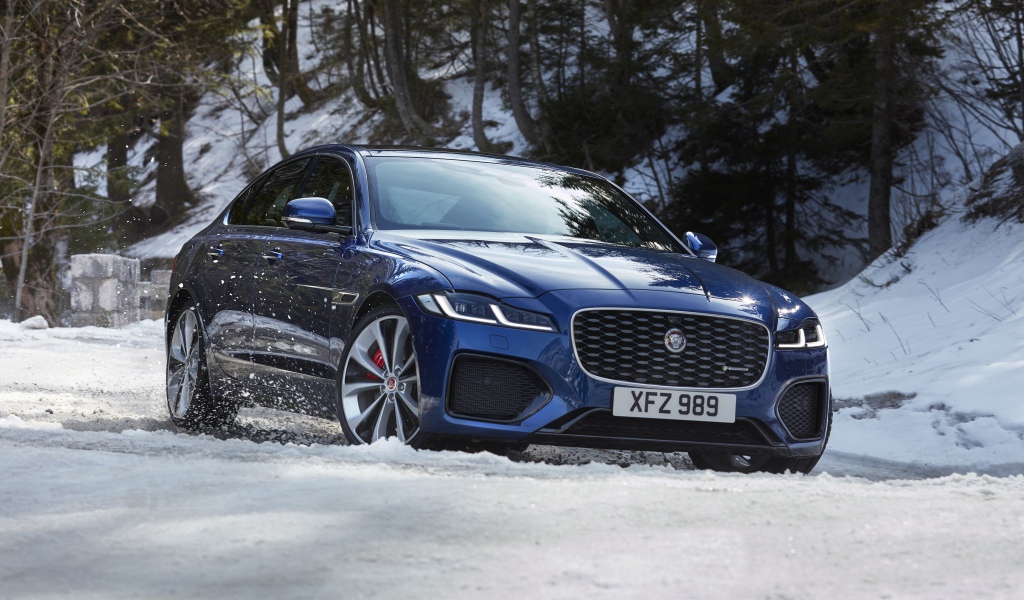 Синий Jaguar XF P300 AWD R-Dynamic 2020 года в заснеженном лесу 