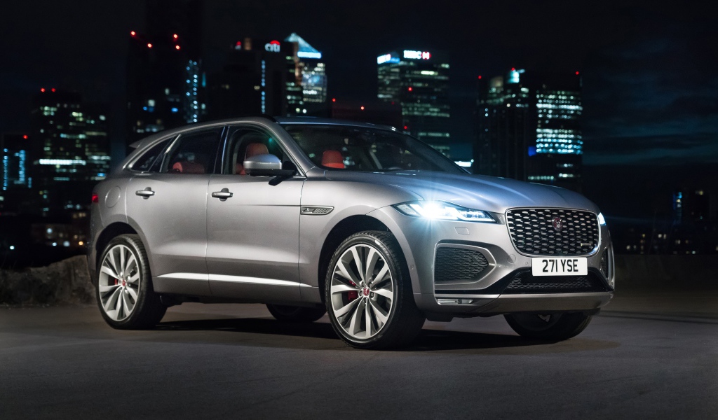 Серебристый Jaguar F-Pace R-Dynamic 2020 года на фоне ночного мегаполиса 