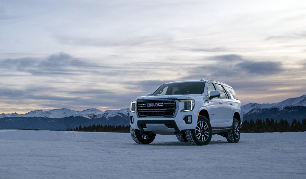 Белый внедорожник  GMC Yukon AT4, 2021 года на фоне заснеженных гор 