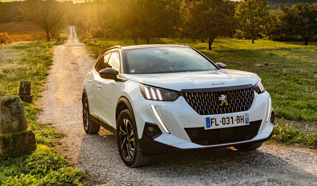 Белый внедорожник Peugeot 2008 GT Line 2019 года на дороге в лесу