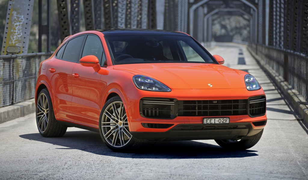Оранжевый внедорожник Porsche Cayenne Turbo Coupe 2019 года на мосту