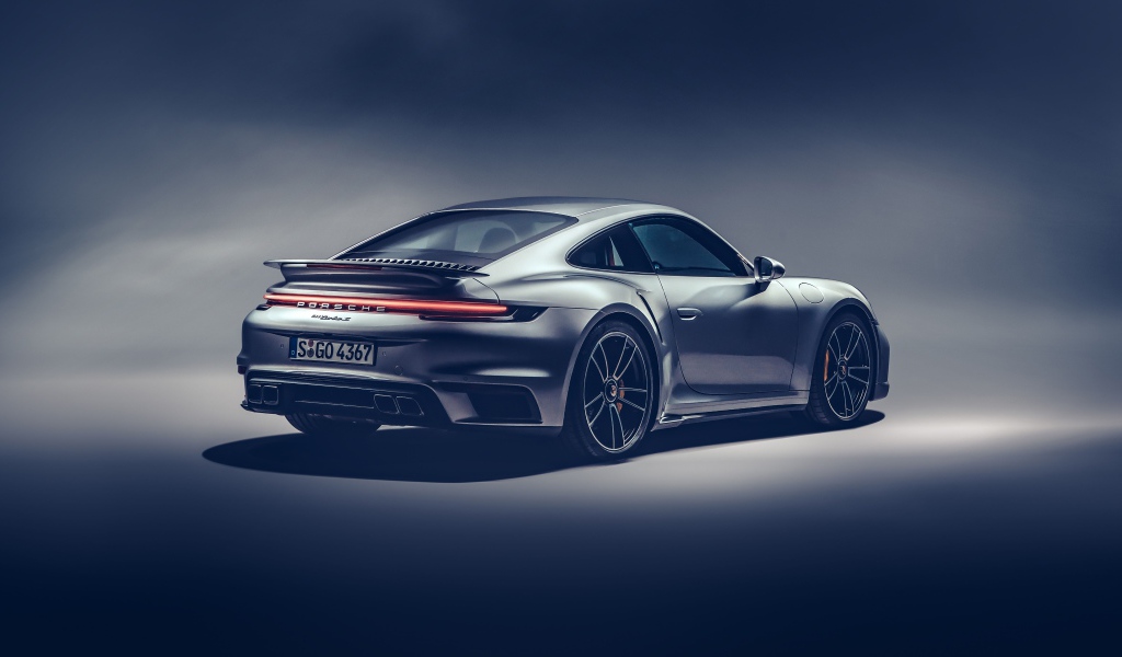 Автомобиль Porsche 911 Turbo S 2020 года на сером фоне вид сзади