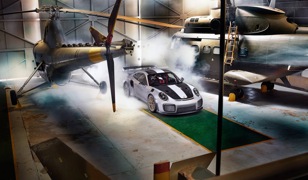 Автомобиль Porsche 911 GT2 RS в ангаре с вертолетами