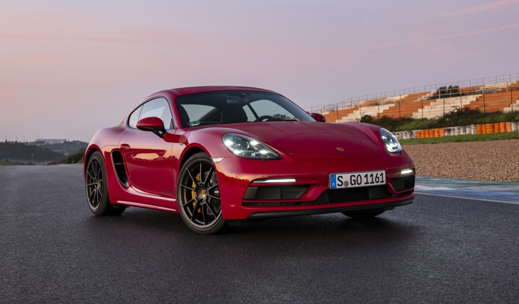 Красный автомобиль Porsche 718 Cayman GTS 4,  2020  года на стадионе
