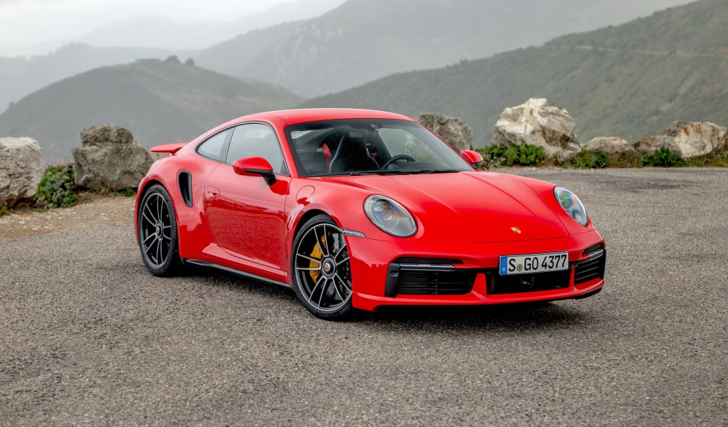 Красный автомобиль Porsche 911 Turbo S 2020 года на фоне гор 