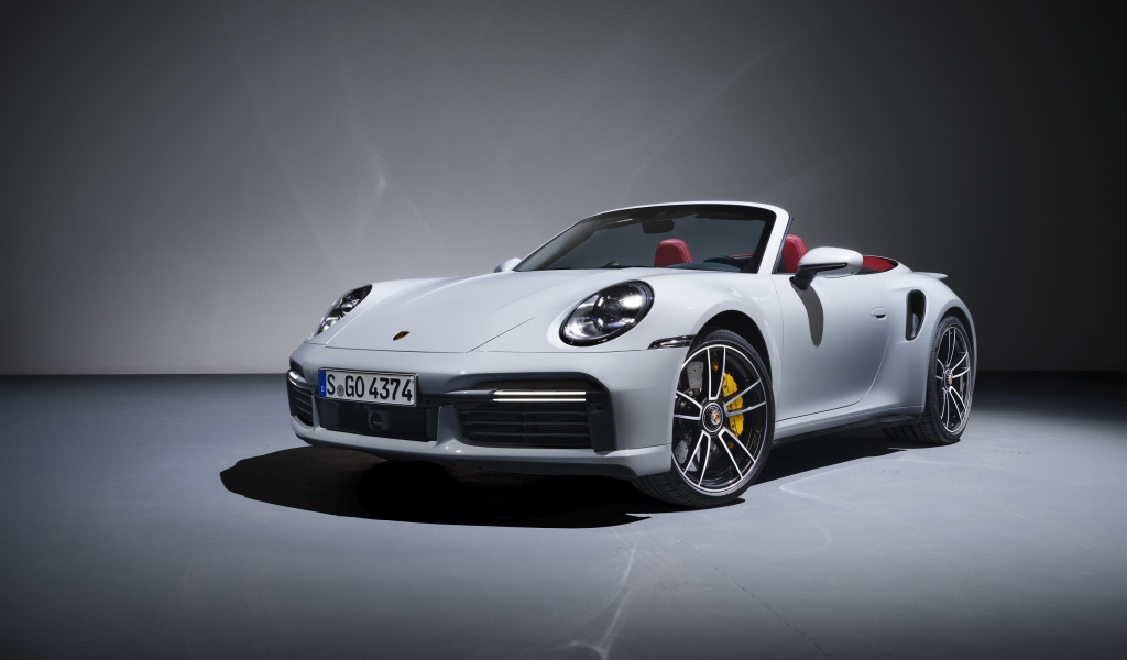 Белый кабриолет Porsche 911 Turbo S 2020 года на сером фоне