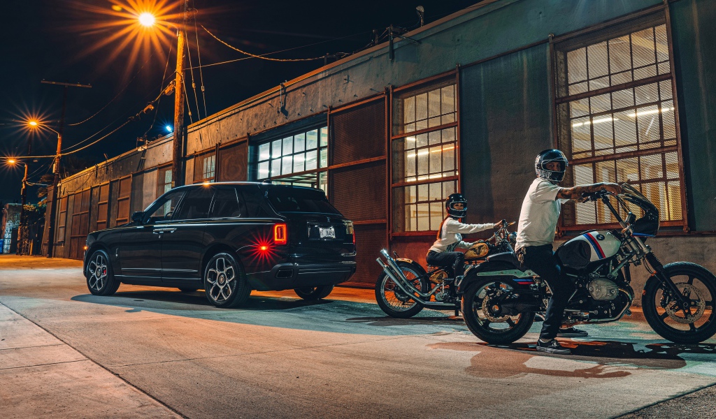 Черный автомобиль Rolls-Royce Cullinan, 2020 года у гаража с байкерами