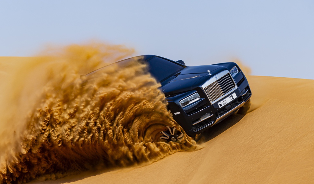 Черный Rolls-Royce Cullinan дрифтует по песку 