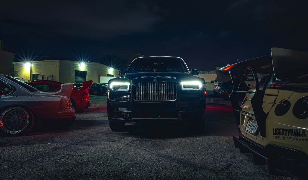 Черный дорогой автомобиль  Rolls-Royce Cullinan, 2020 года с включенными фарами