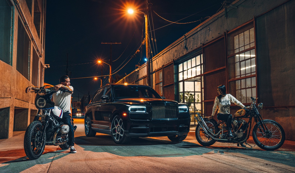 Черный стильный автомобиль Rolls-Royce Cullinan на улице города с байкерами