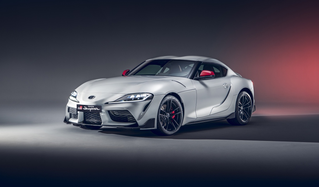 Серебристый автомобиль Toyota GR Supra 2L 2020 года на сером фоне