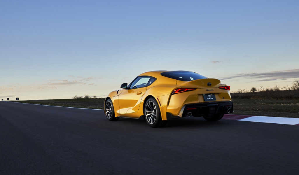 Желтый автомобиль Toyota GR Supra, 2021 года на трассе вид сзади