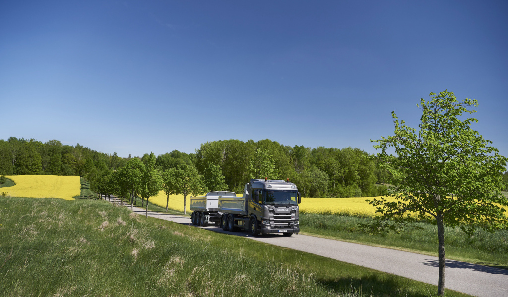 Грузовик Scania Trucks на трассе у поля