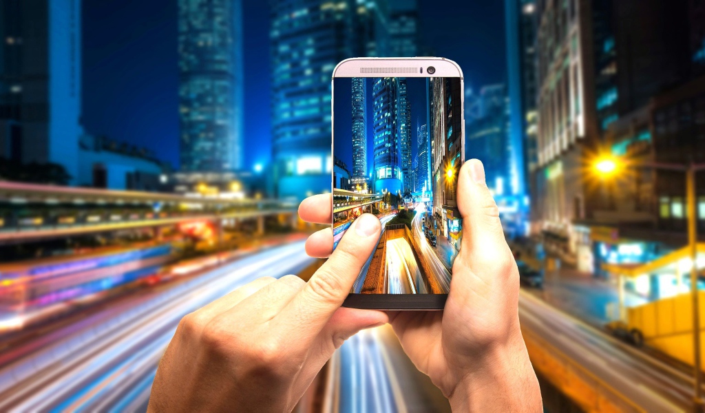 Мужчина делает фото ночного города на смартфон 