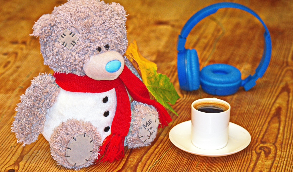 Медведь на столе с чашкой кофе и наушниками 