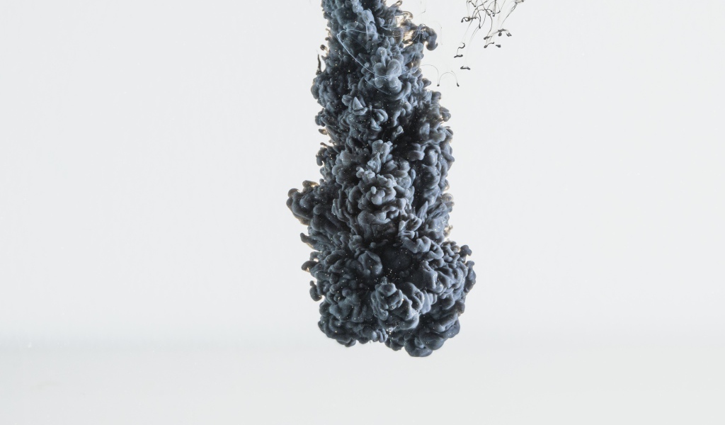 Черная краска растворяется в воде на белом фоне 