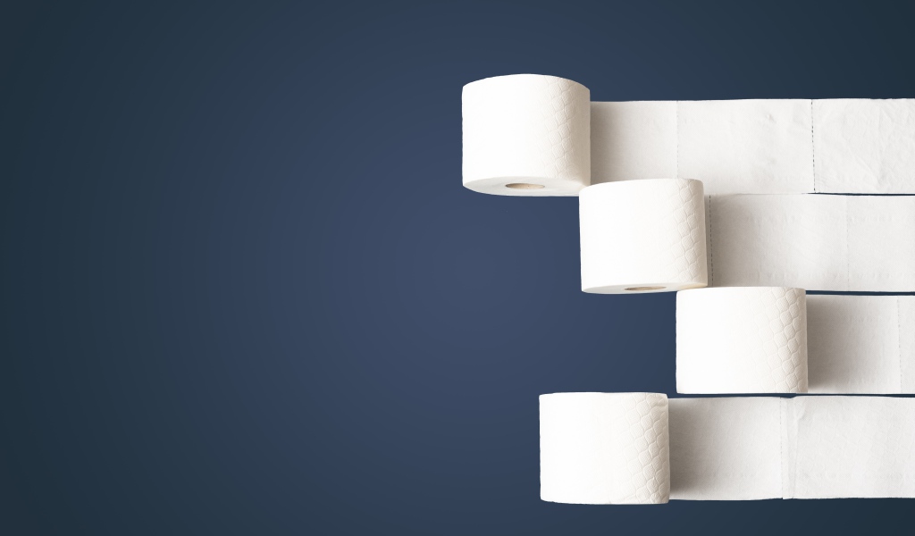 Четыре рулона белой туалетной бумаги на сером фоне