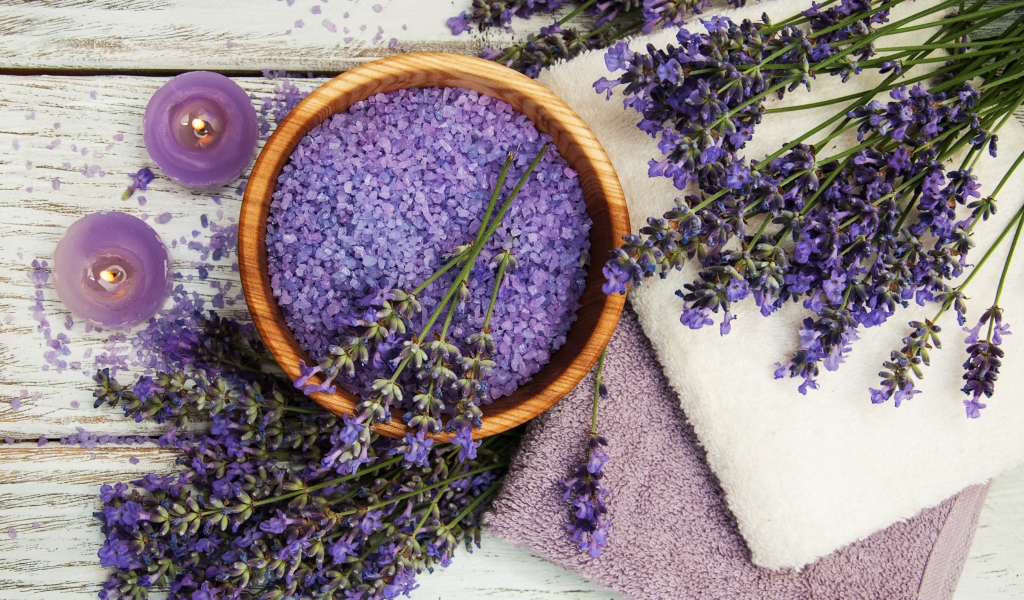 Ароматная соль, на столе с полотенцами, лавандой и зажженными свечами