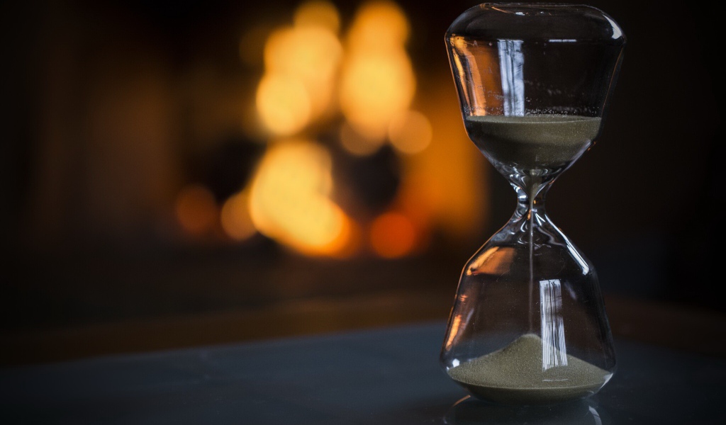 Стеклянные песочные часы на столе 