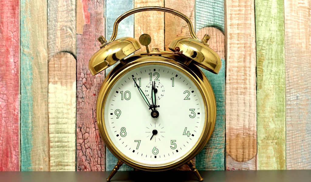Золотой будильник стоит у стены 