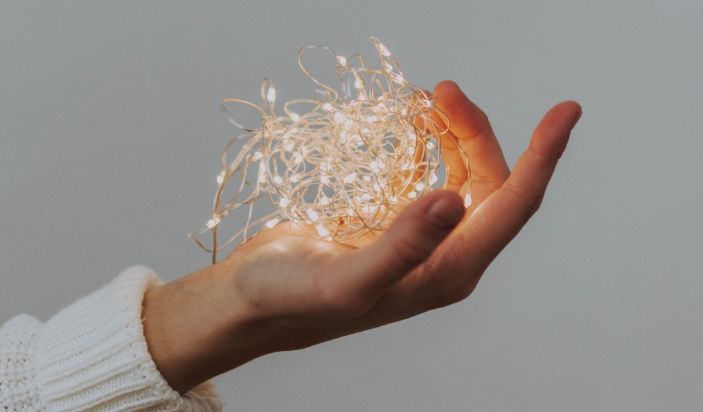 Включенная гирлянда в руке на сером фоне