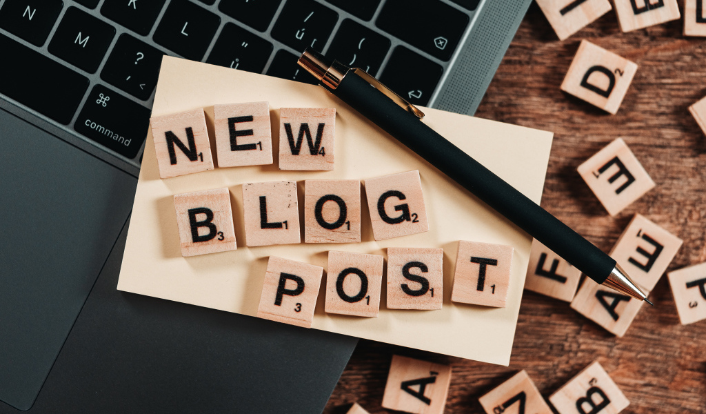 Надпись на английском New Blog Post возле ноутбука с ручкой 